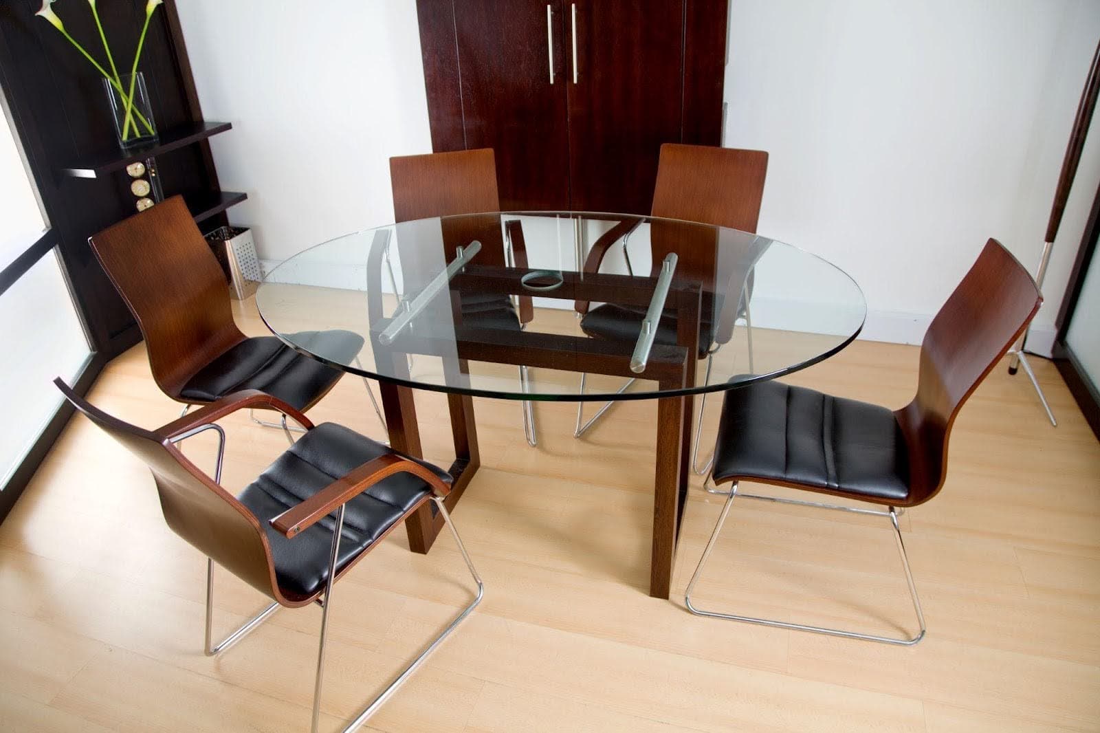 A glass dining table surrounded by four chairs elegantly arranged for a meal setting