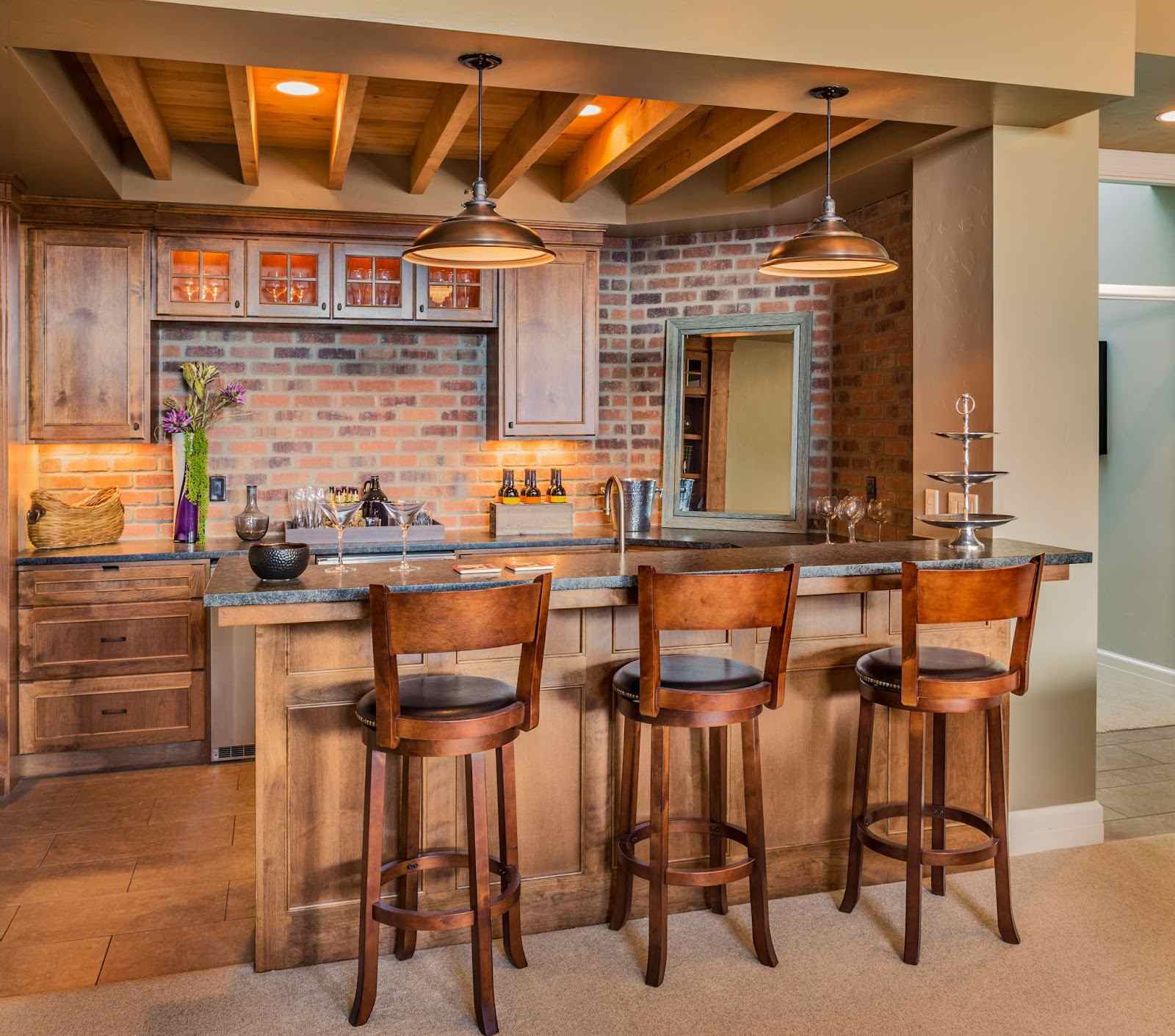 Modern kitchen with wooden bar stools, brick wall, and pendant lights.