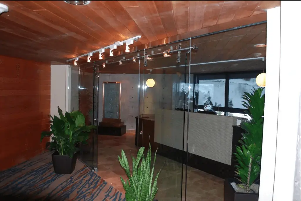 Modern office space with glass walls, green plants, and a potted plant for a fresh atmosphere.