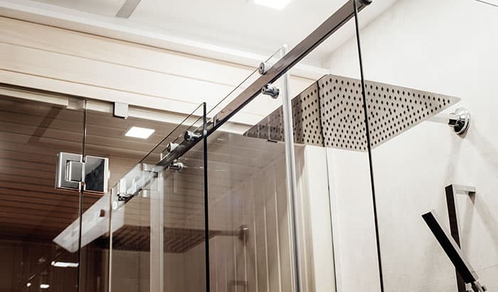 Glass shower door with shower head inside bathroom.