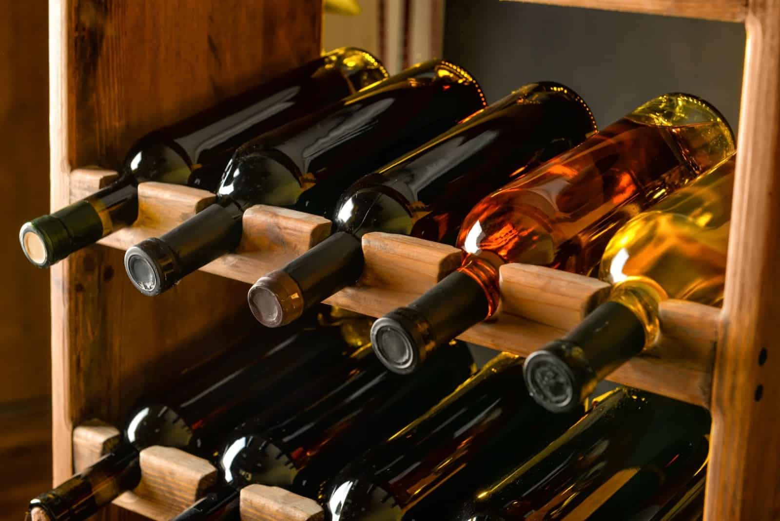 Glass enclosed wine cellar features wooden rack with wine bottles.