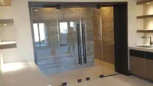 A glass door separates a kitchen from a shower area creating an unusual blend of home spaces